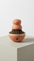 Modern terracotta utility brush with base, Three-quarter angle with slight overhead perspective that highlights form and...